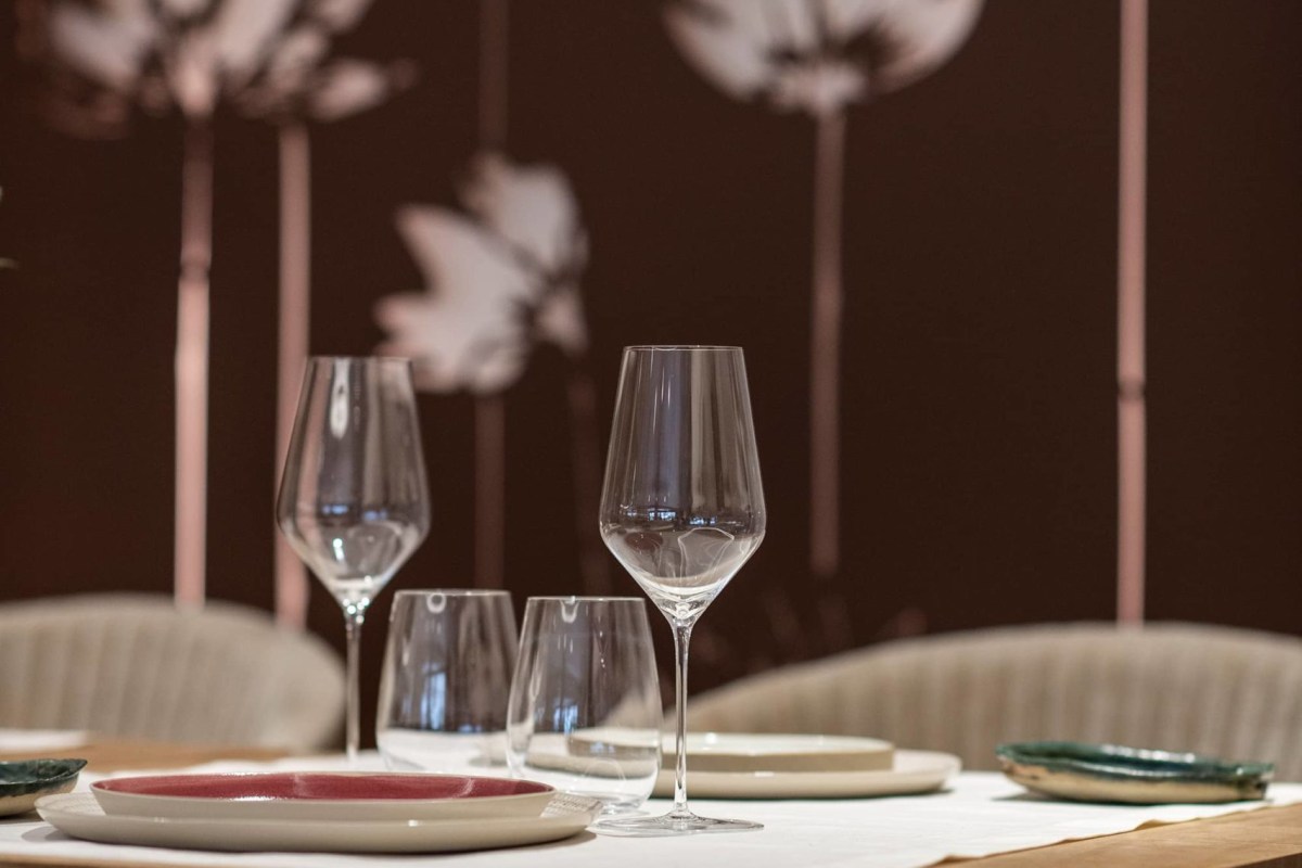 Elegant table setting with wine glasses, plates, and leaf-patterned wall decor