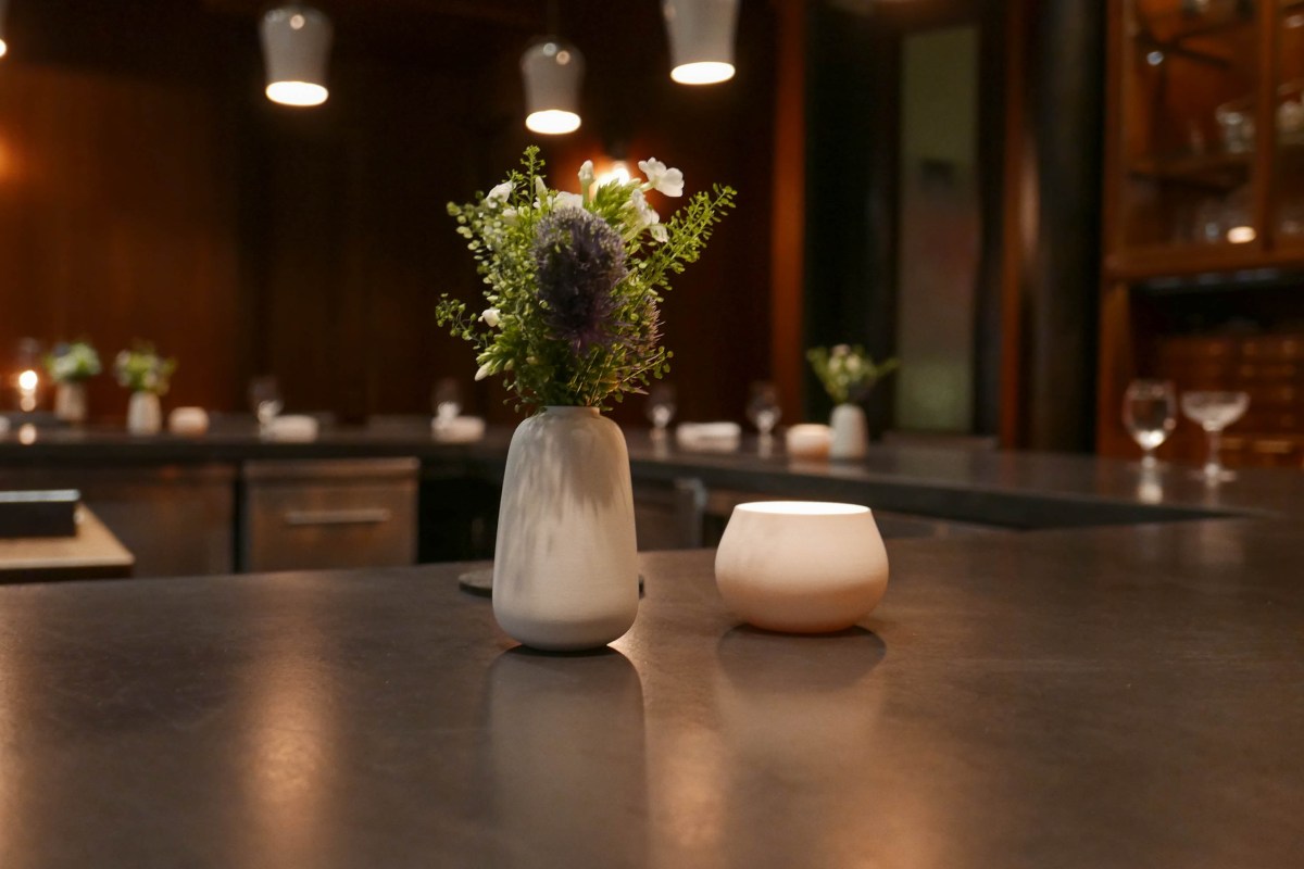 Bar/dining counter at Atera with small flower vase and candle, warm wood interior in background