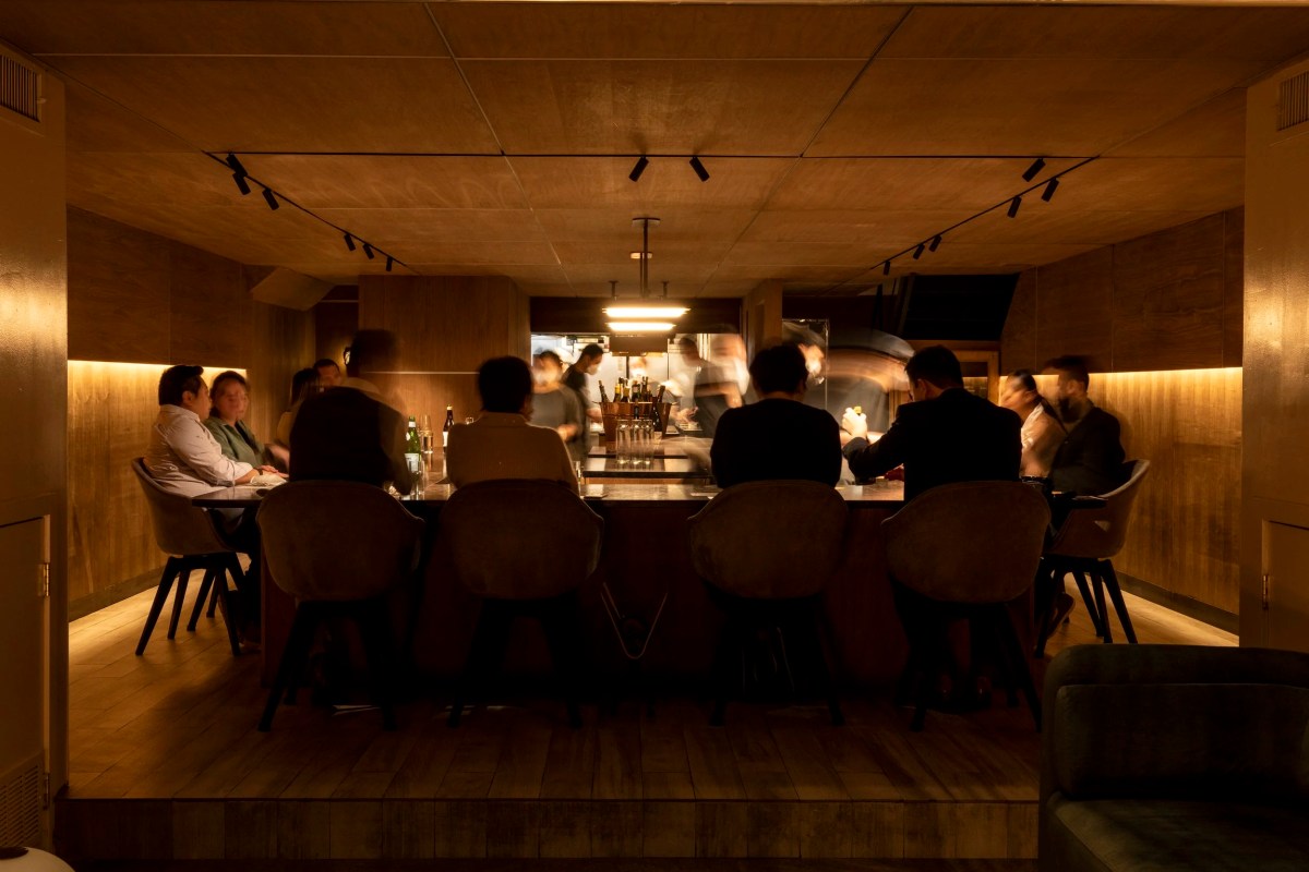 Dimly lit restaurant bar and dining counter with wooden walls and people seated at the counter