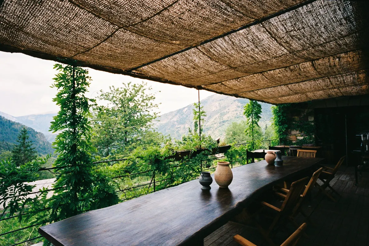 The covered terrace of L'Auberge de la Roche in Valdeblore, with a long wooden table facing the mountains of the Mercantour