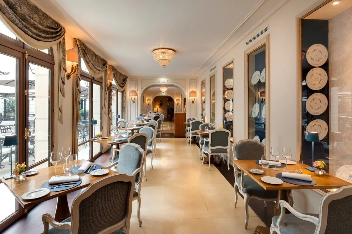 Elegant hotel restaurant with set tables, blue upholstered chairs, and decorative plates on the wall