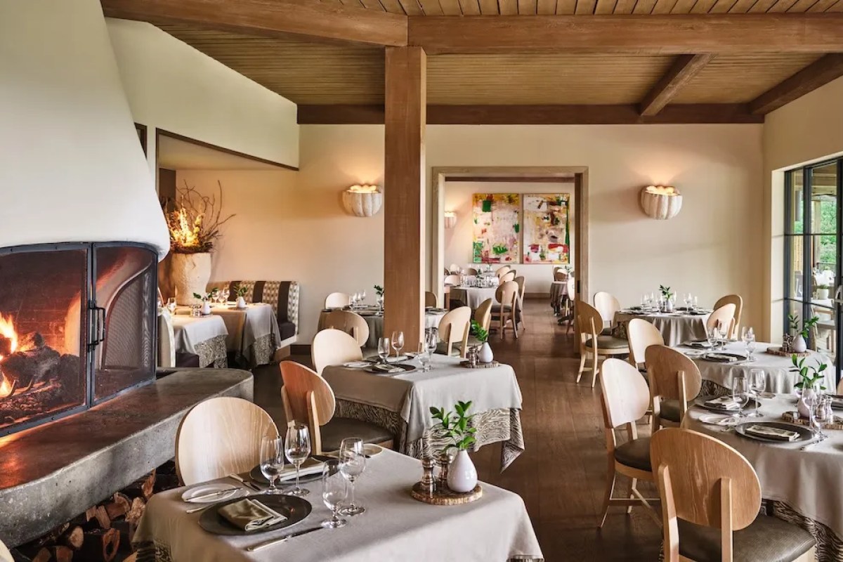 Elegant restaurant dining room with wood beam ceiling, fireplace, and set tables