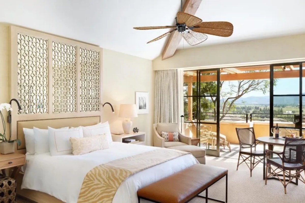 Guest bedroom with king bed, ceiling fan, decorative screen, and balcony view of valley