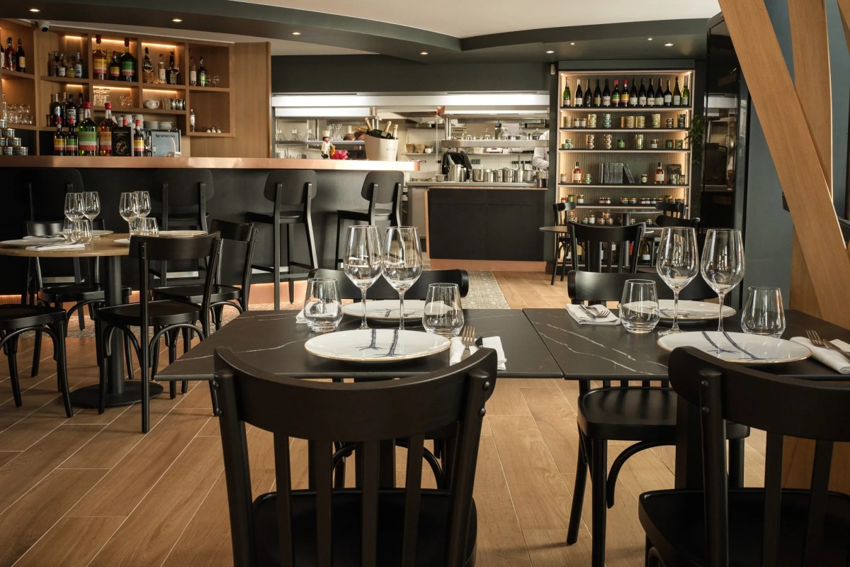 Dining room with bar and open kitchen, tables set with wine glasses and patterned plates