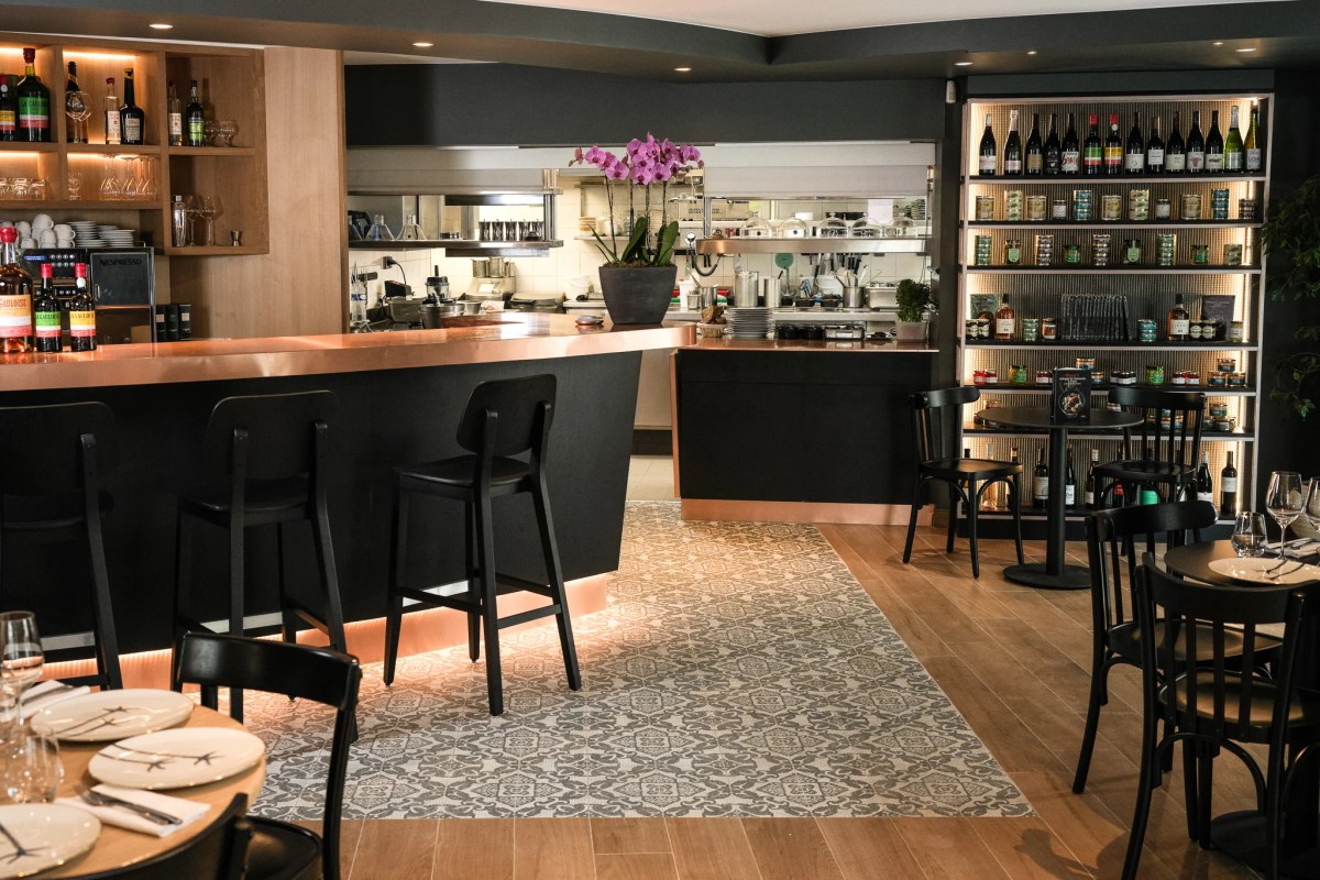 Copper-topped bar counter with orchid, open kitchen and wine shelf, patterned tile floor