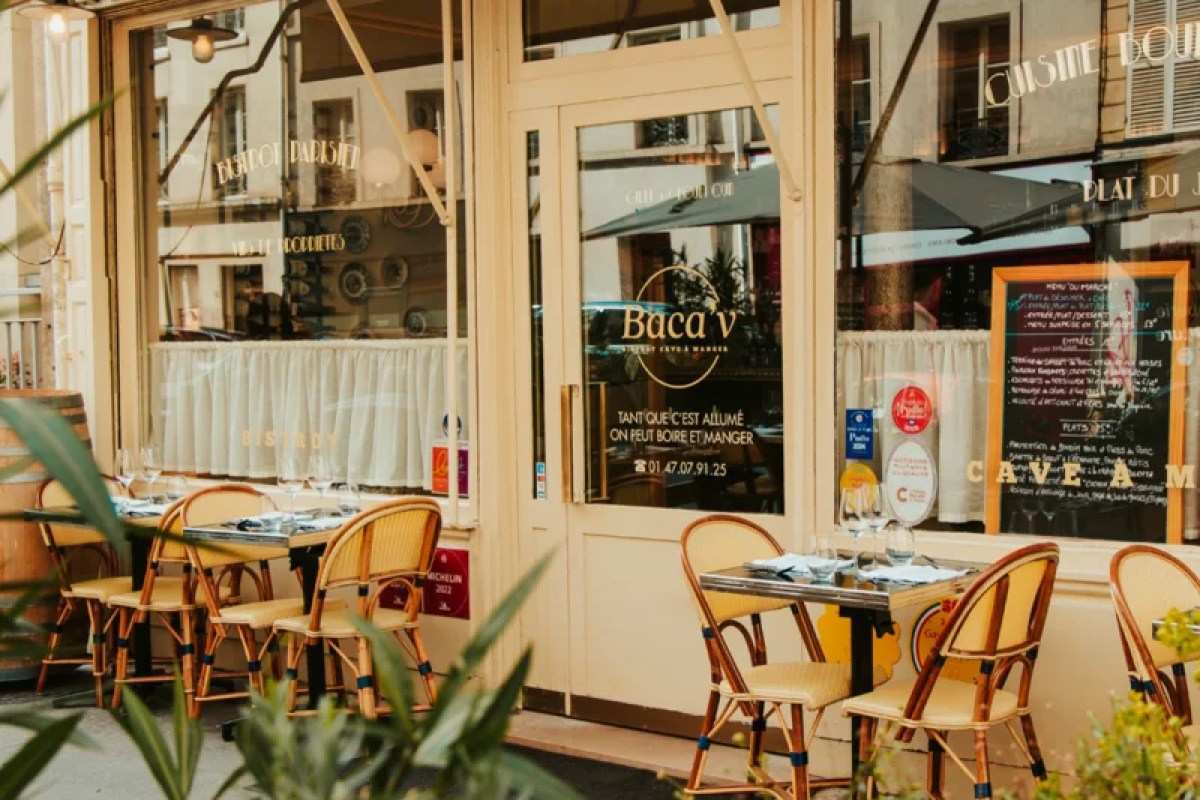 Exterior of Baca'v restaurant with cream facade, outdoor terrace tables and chairs, and signage