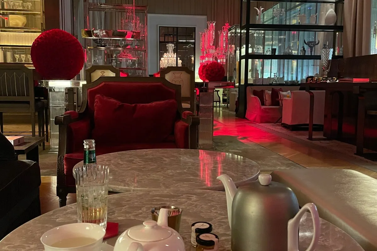 Grand Salon lounge at Baccarat Hotel with red velvet armchairs, crystal chandeliers, and tea service table