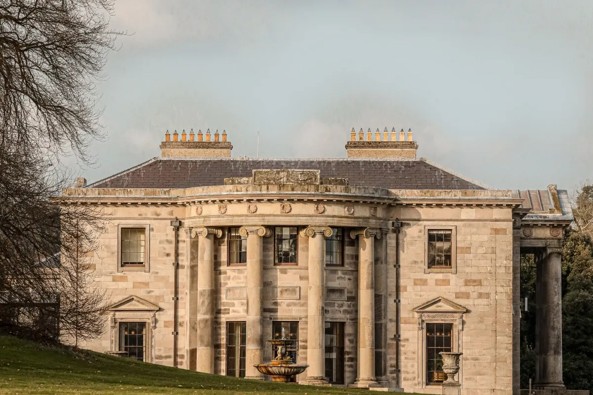 Close-up of Ballyfin Demesne's grand stone façade with columned portico entrance under a pale sky