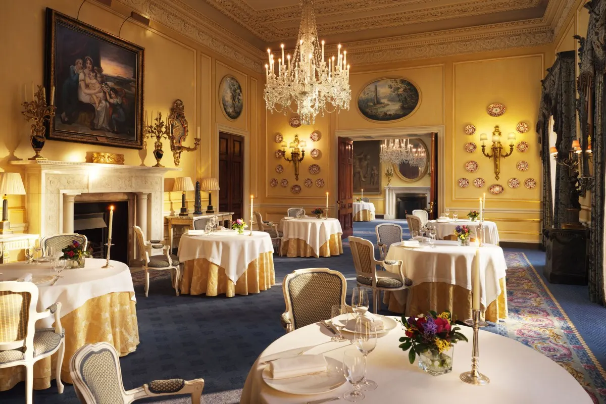 Opulent dining room with fireplace, chandelier, and tables adorned with gold tablecloths