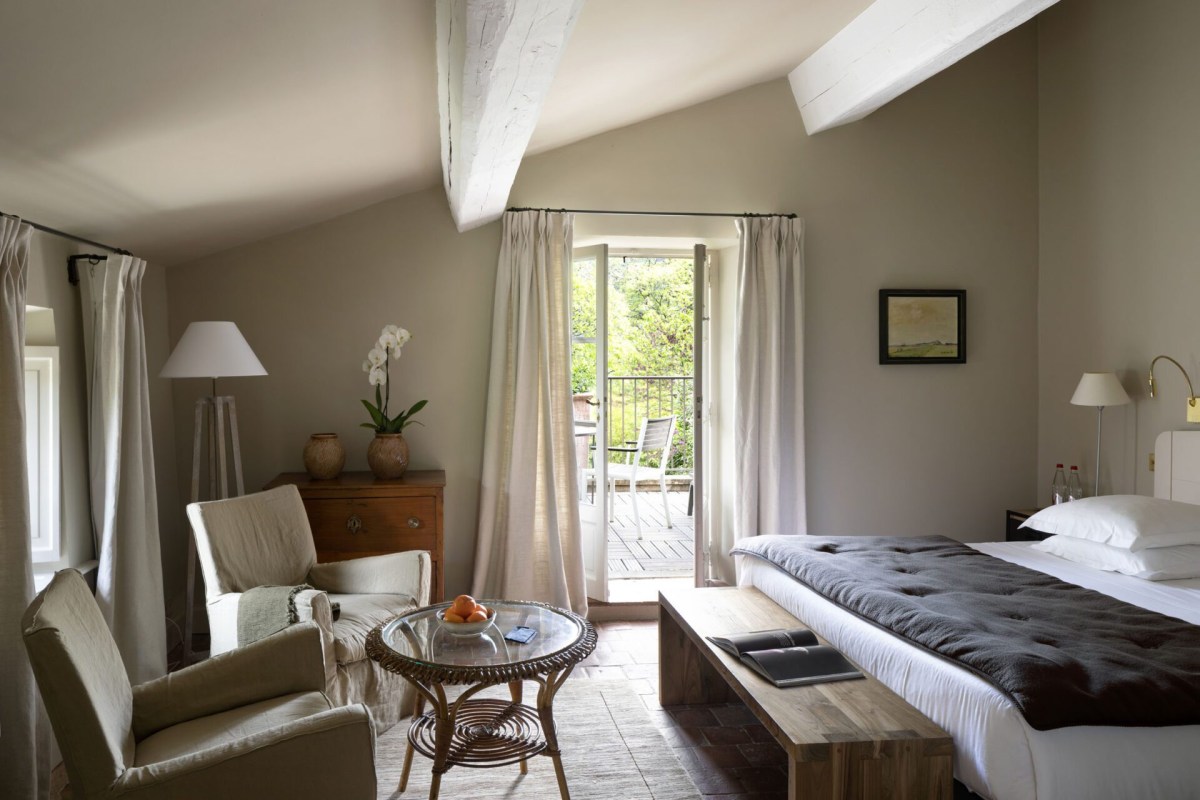 Spacious beamed-ceiling suite with seating area and doors opening to a terrace