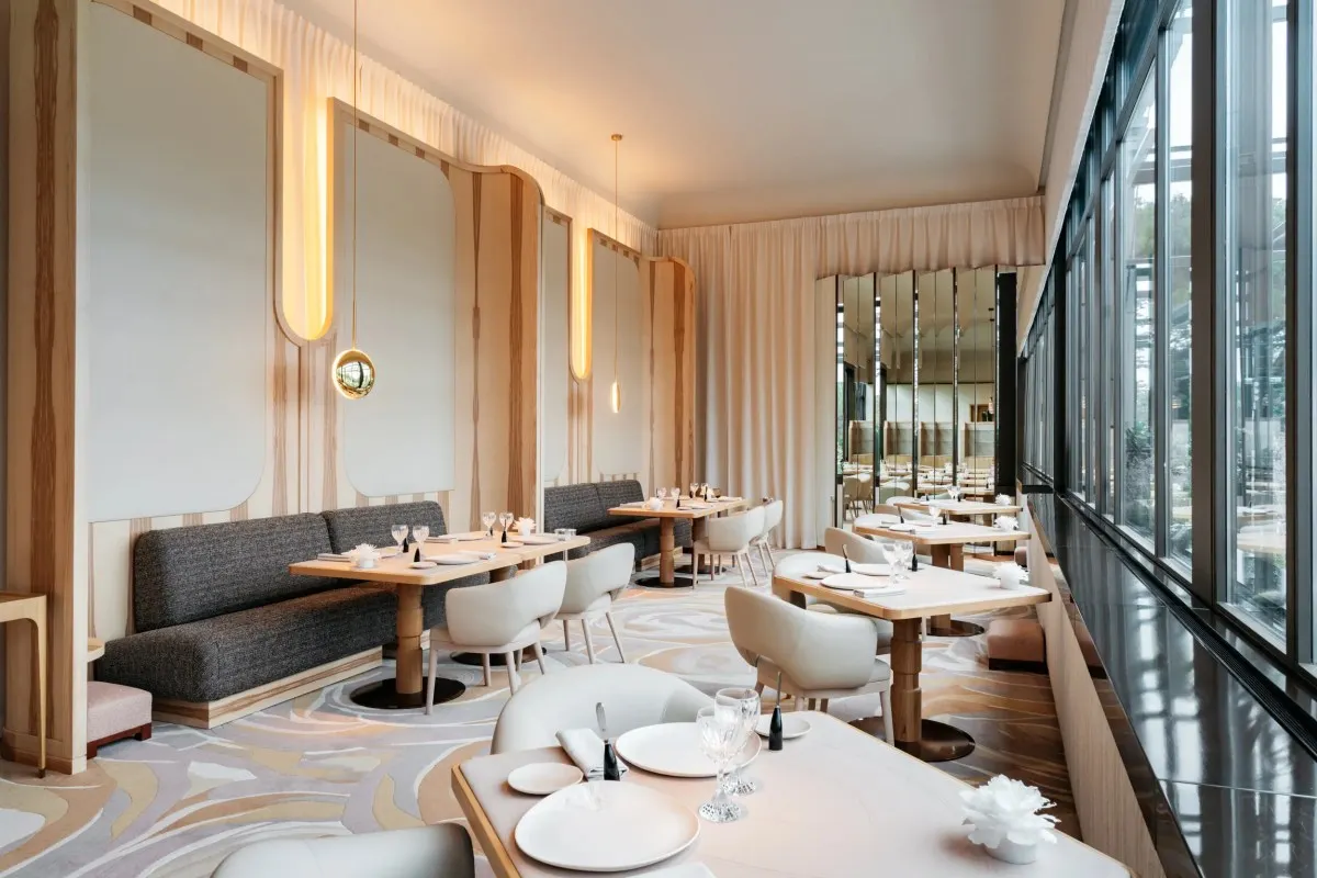 Elegant modern hotel restaurant with wood paneling, patterned carpet and lake-view windows