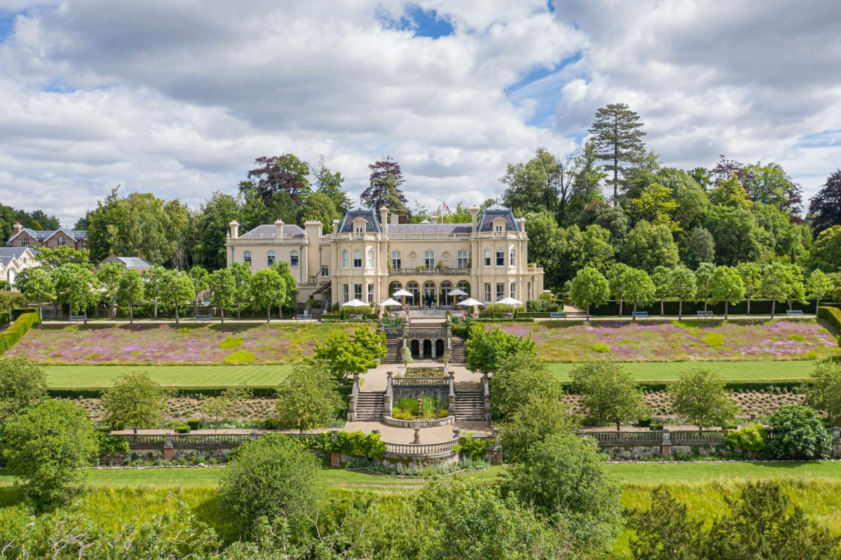 Aerial view of Beaverbrook Surrey mansion with manicured gardens, terraces and fountains under a blue sky