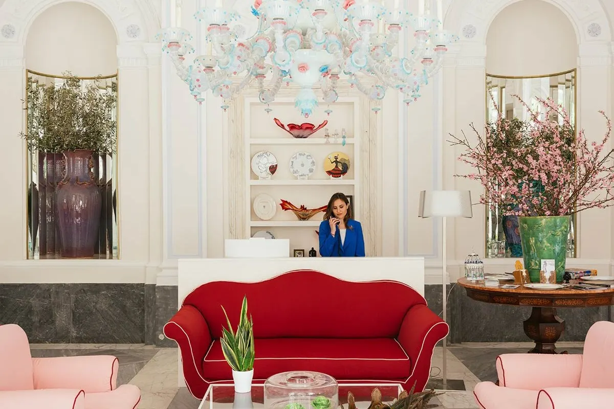 Elegant hotel lobby with red sofa, chandelier, and reception desk