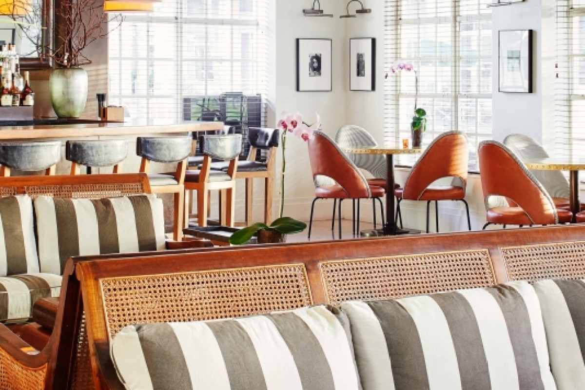 Elegant hotel bar and lounge area with striped banquette seating and orange accent chairs