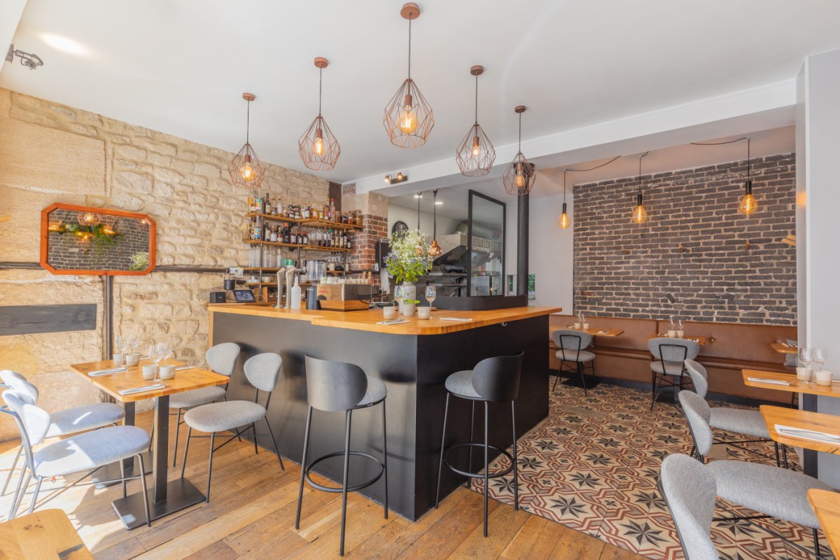 Alternate angle of Biscotte's dining room showing bar, stone and brick walls, wooden tables and tiled floor