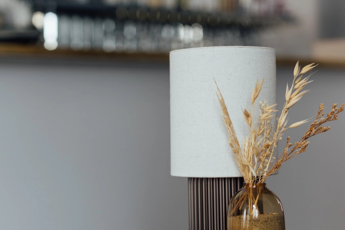 Decorative lamp with dried flowers in a vase, blurred bar shelves with glasses in background