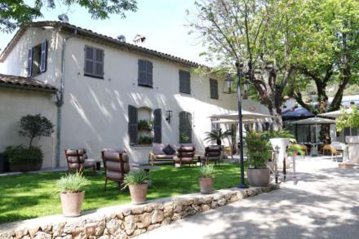 Provençal building exterior with terrace, lounge chairs and potted plants under trees