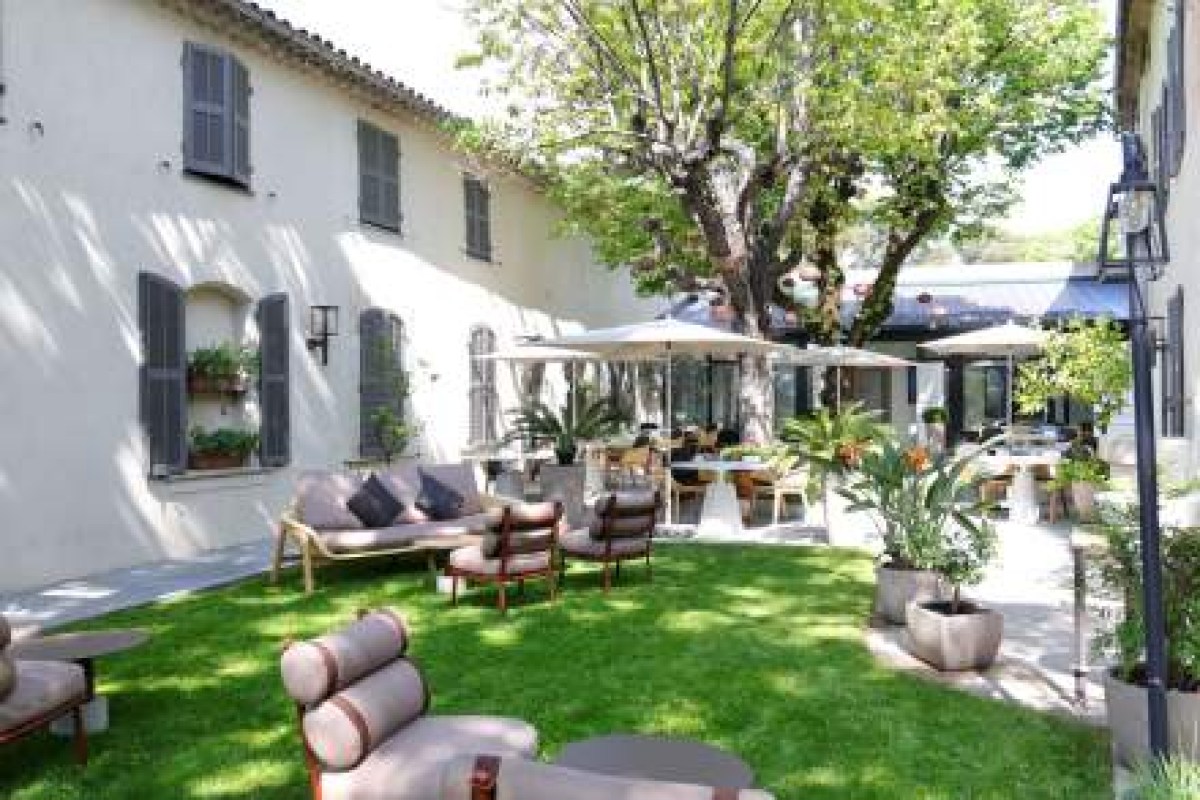 Courtyard view of the restaurant building with terrace seating and manicured garden