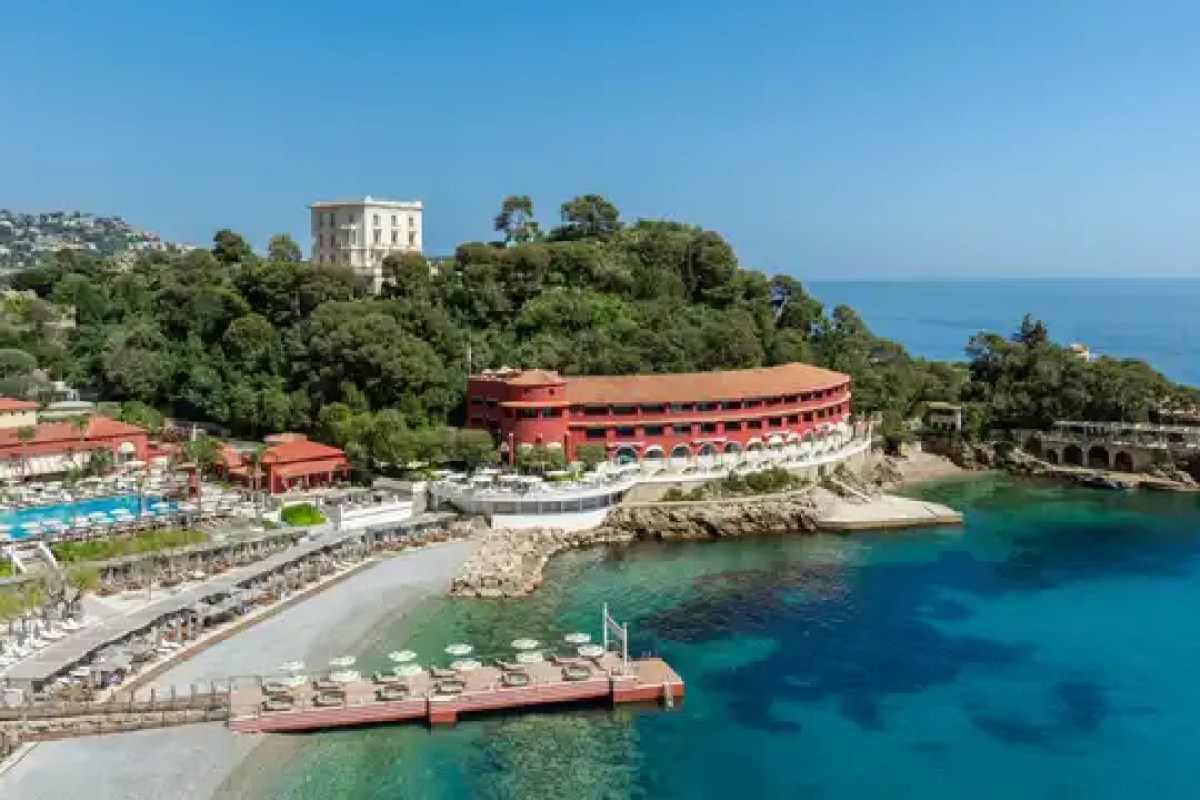 Aerial view of the red circular Radisson Blu Hotel building on the Monaco coastline, home to Blue Bay Marcel Ravin restaurant