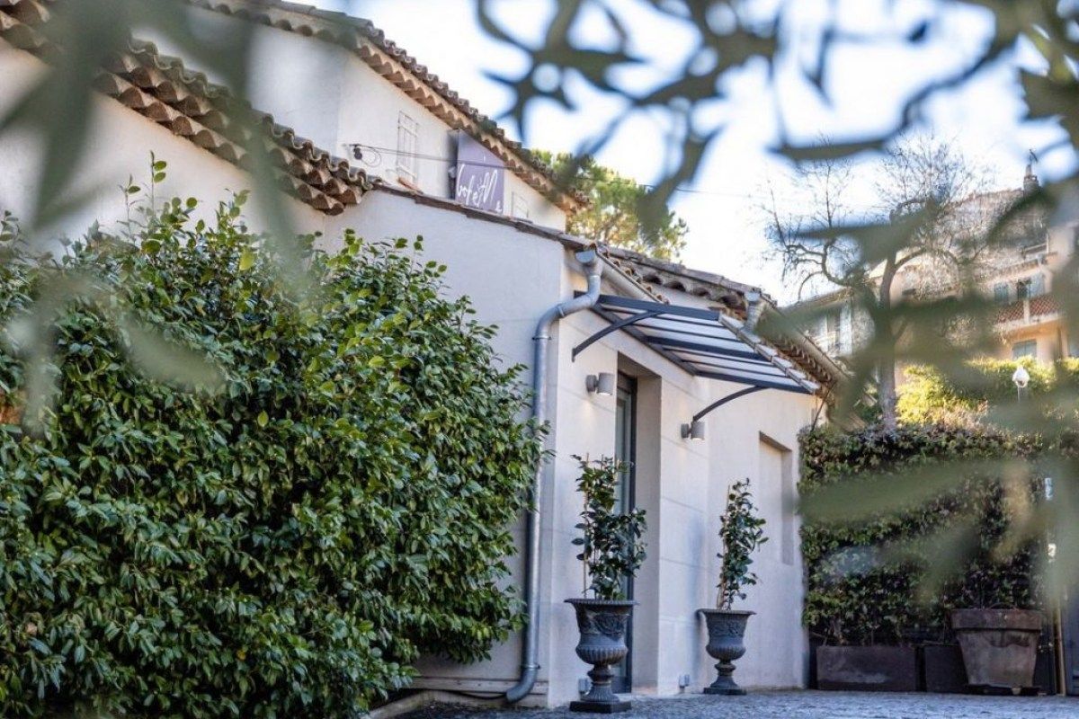 Exterior view of Bohème restaurant entrance in Mougins, with awning, topiary plants in urns, and climbing greenery