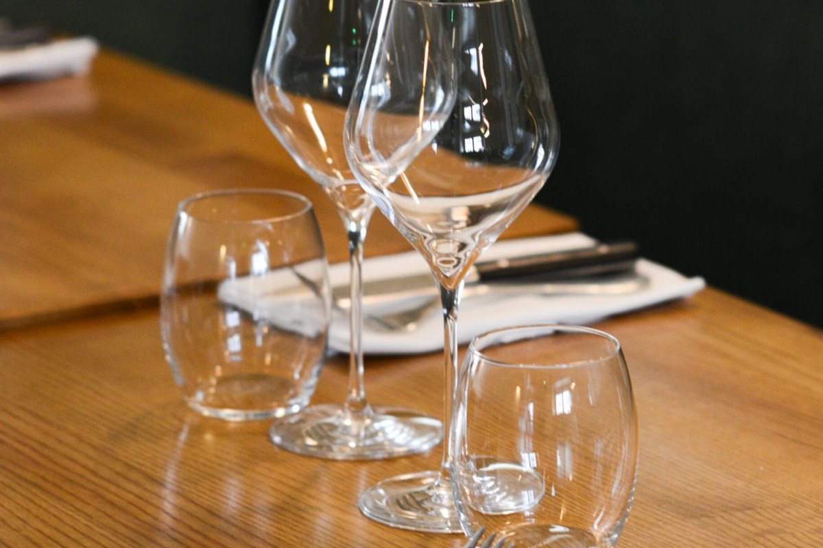 Close-up of wine and water glasses set on a wooden table with napkin and cutlery