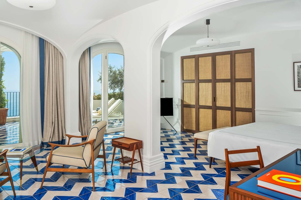 Guest suite with blue and white patterned tile floor, seating area and sea-view balcony