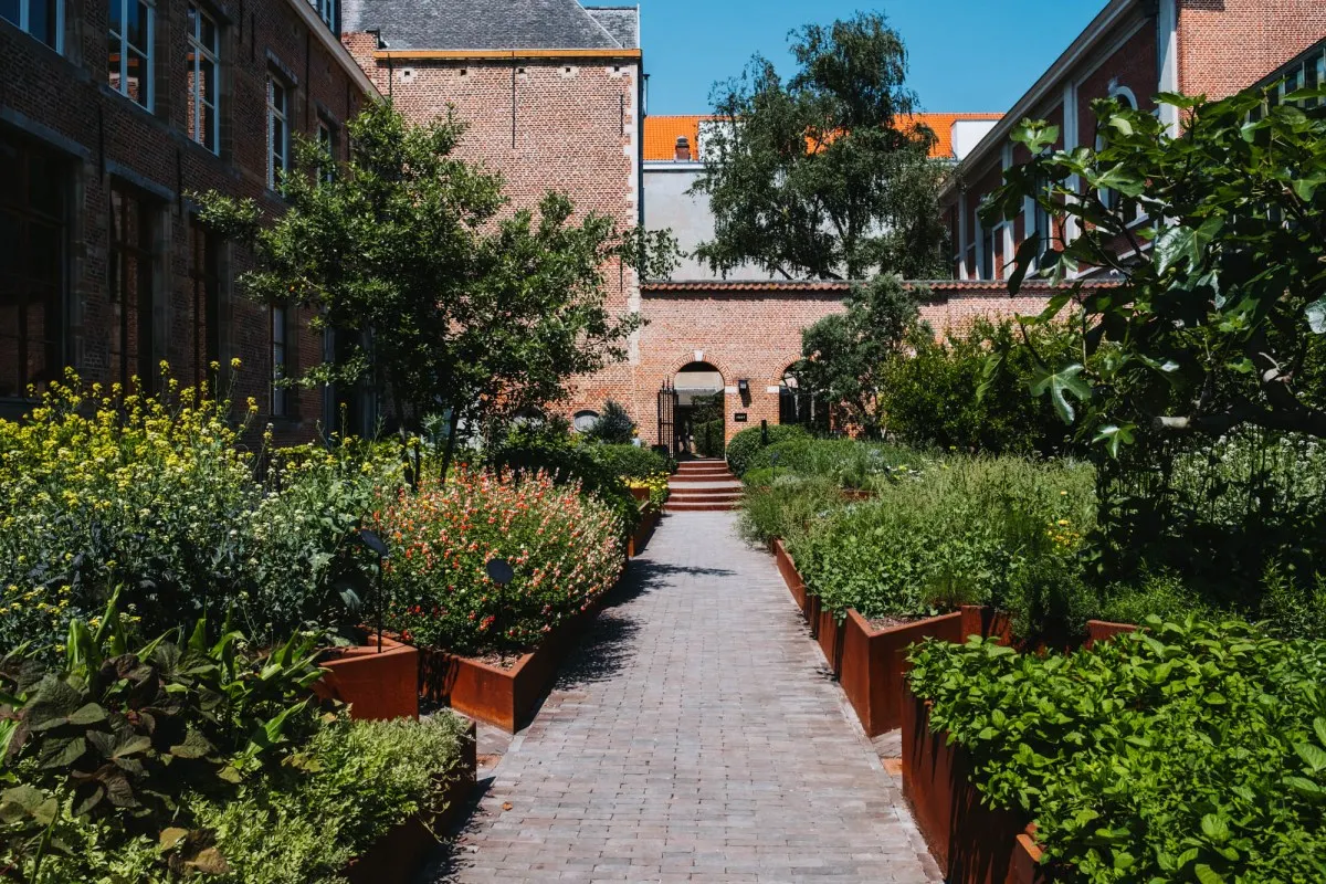 The brick monastery buildings of Botanic Sanctuary Antwerp around a planted cloister garden with a paved path