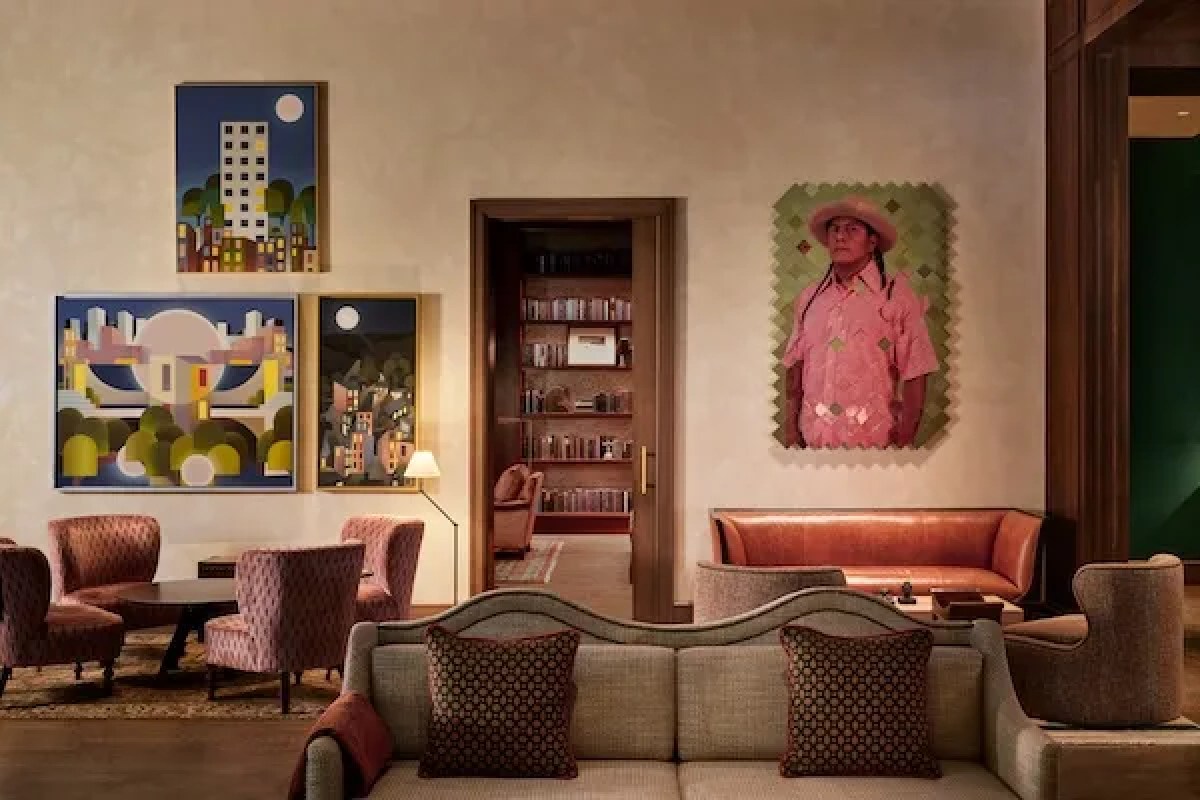 Hotel lounge with eclectic artwork, sofas and armchairs leading to a library room