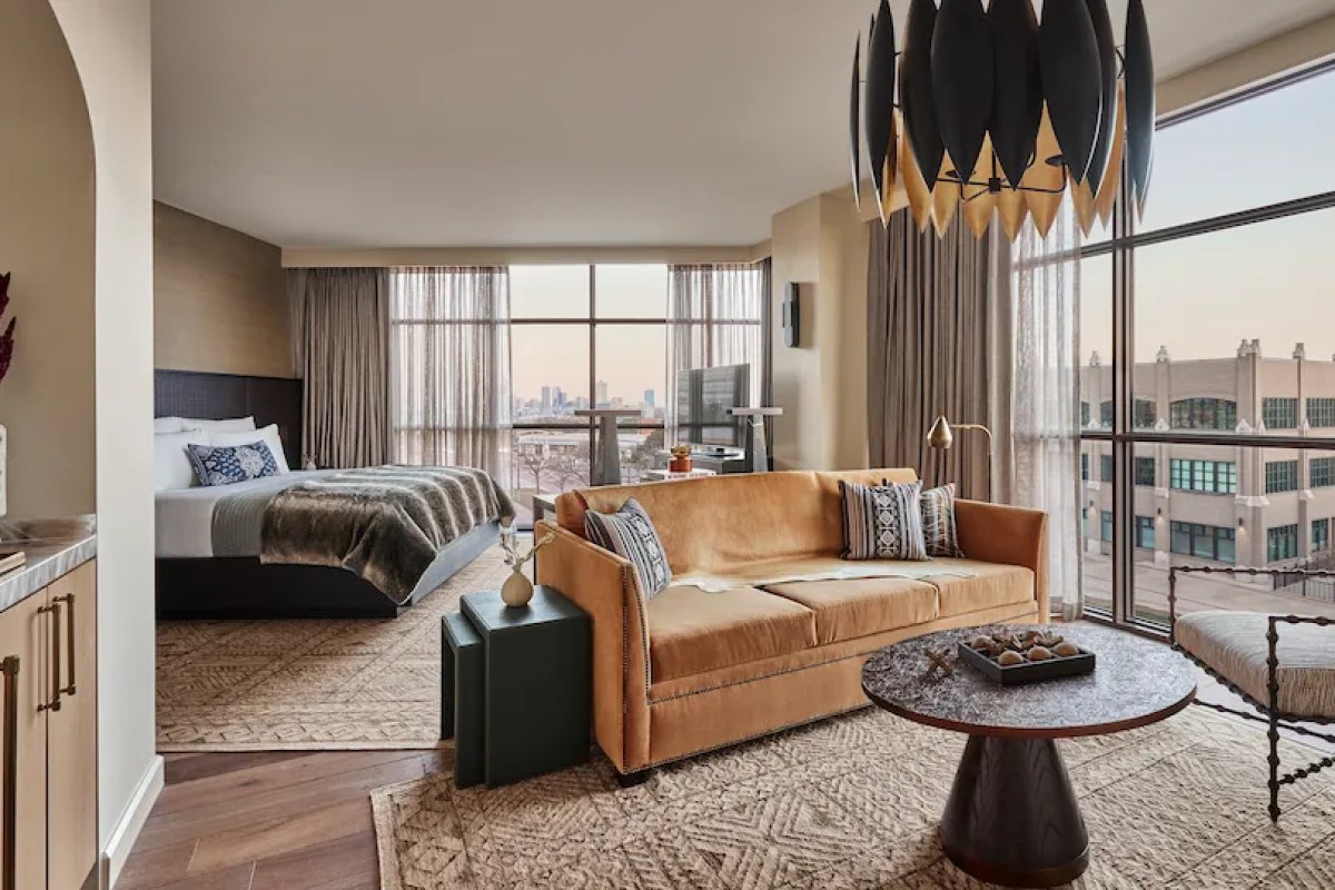 Guest suite with bed, orange sofa, coffee table and large windows showing city skyline