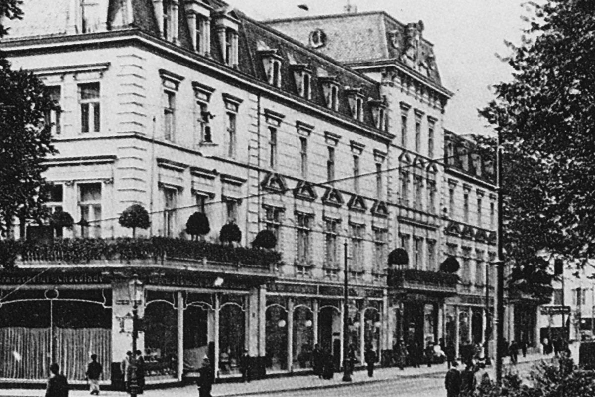 Historic black-and-white photo of the Breidenbacher Hof building's ornate façade with mansard roofs on a Düsseldorf street.
