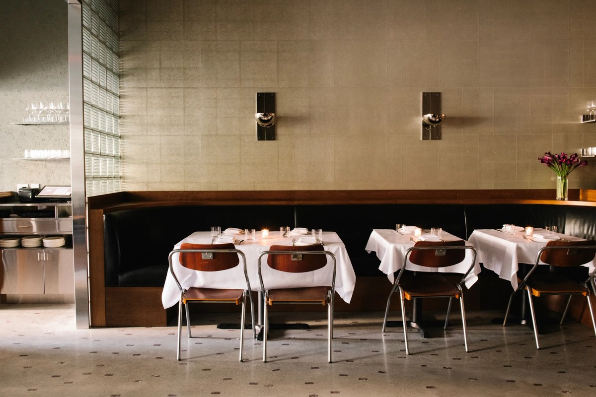 Dining room with booth seating, set tables, candles, and flowers