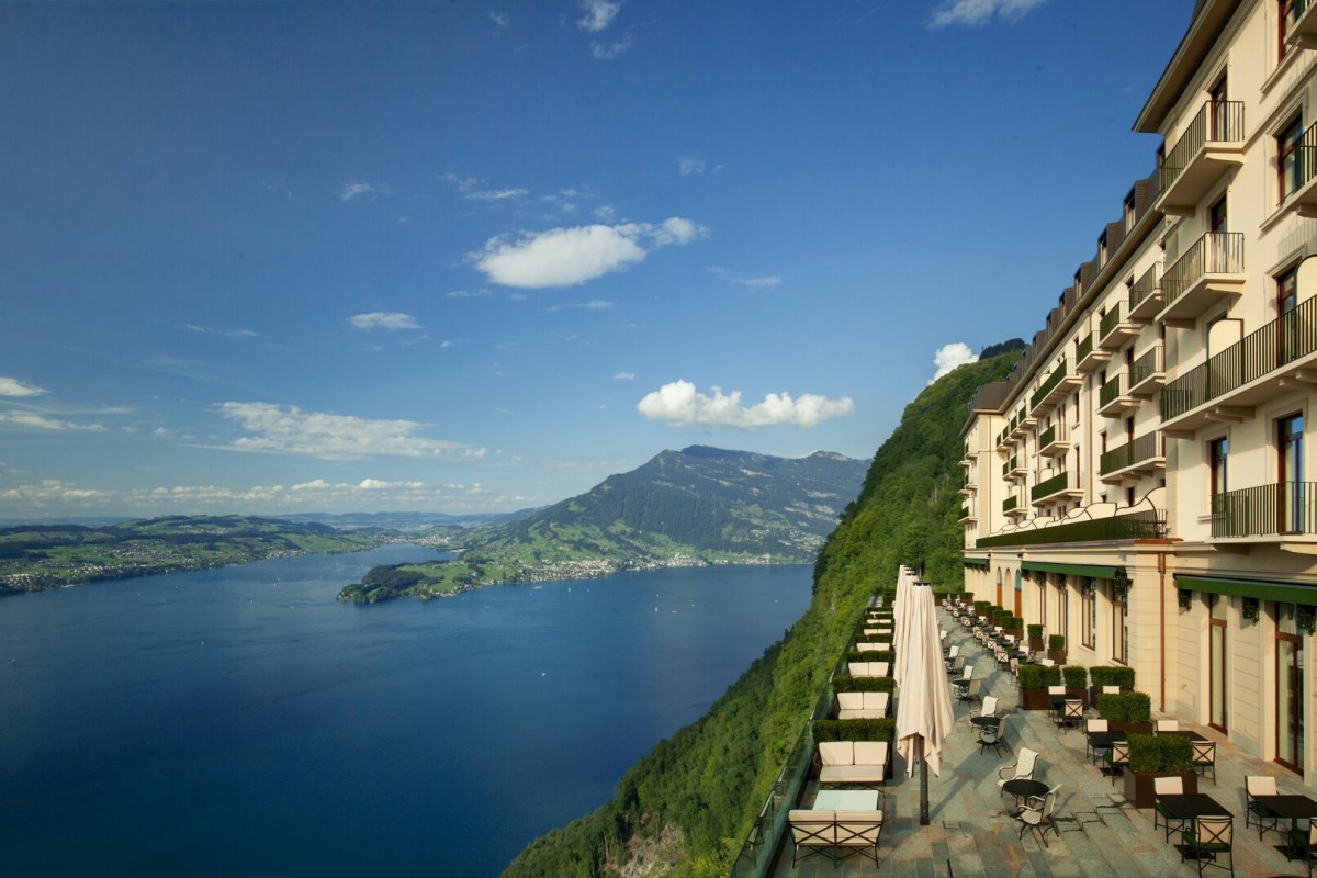 Aerial view of Bürgenstock Hotel's façade and terrace overlooking Lake Lucerne with mountains in the background