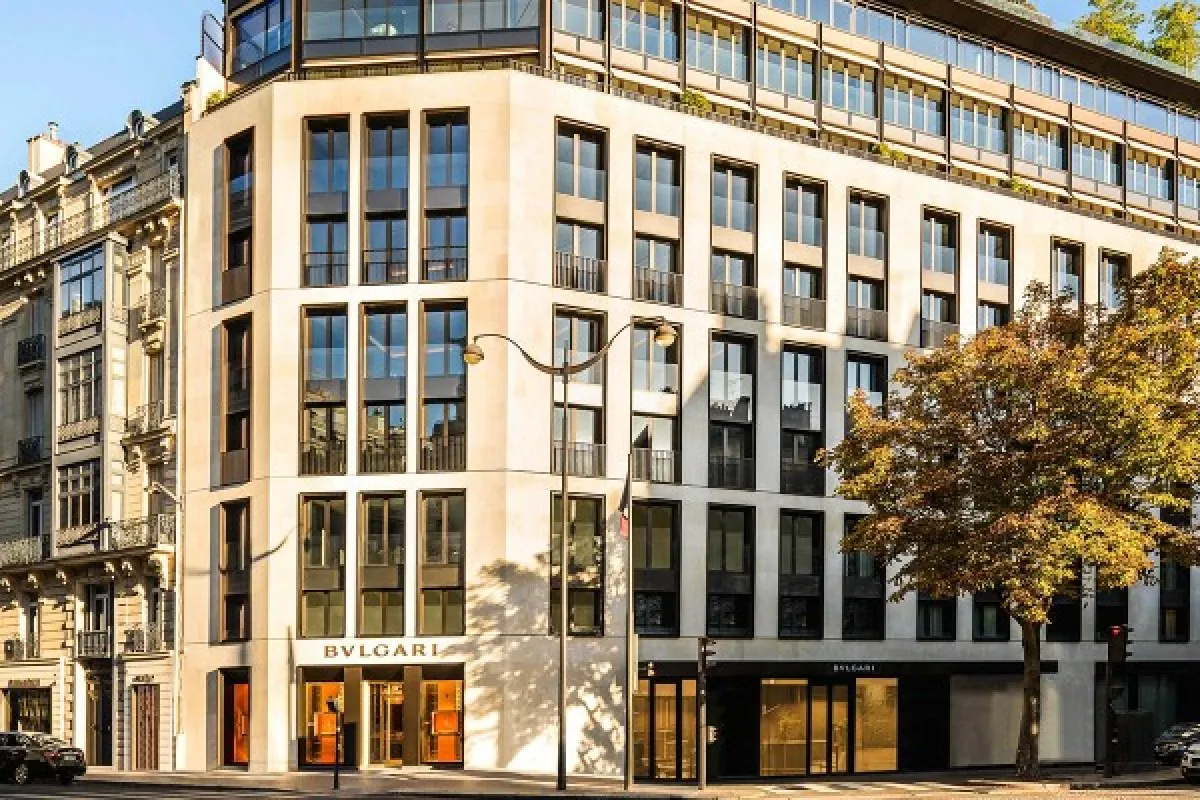 Exterior façade of the Bvlgari Hôtel Paris building with large windows, stone finish, trees and street view.