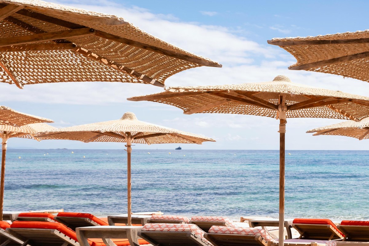 Woven straw umbrellas framing a view of the turquoise sea