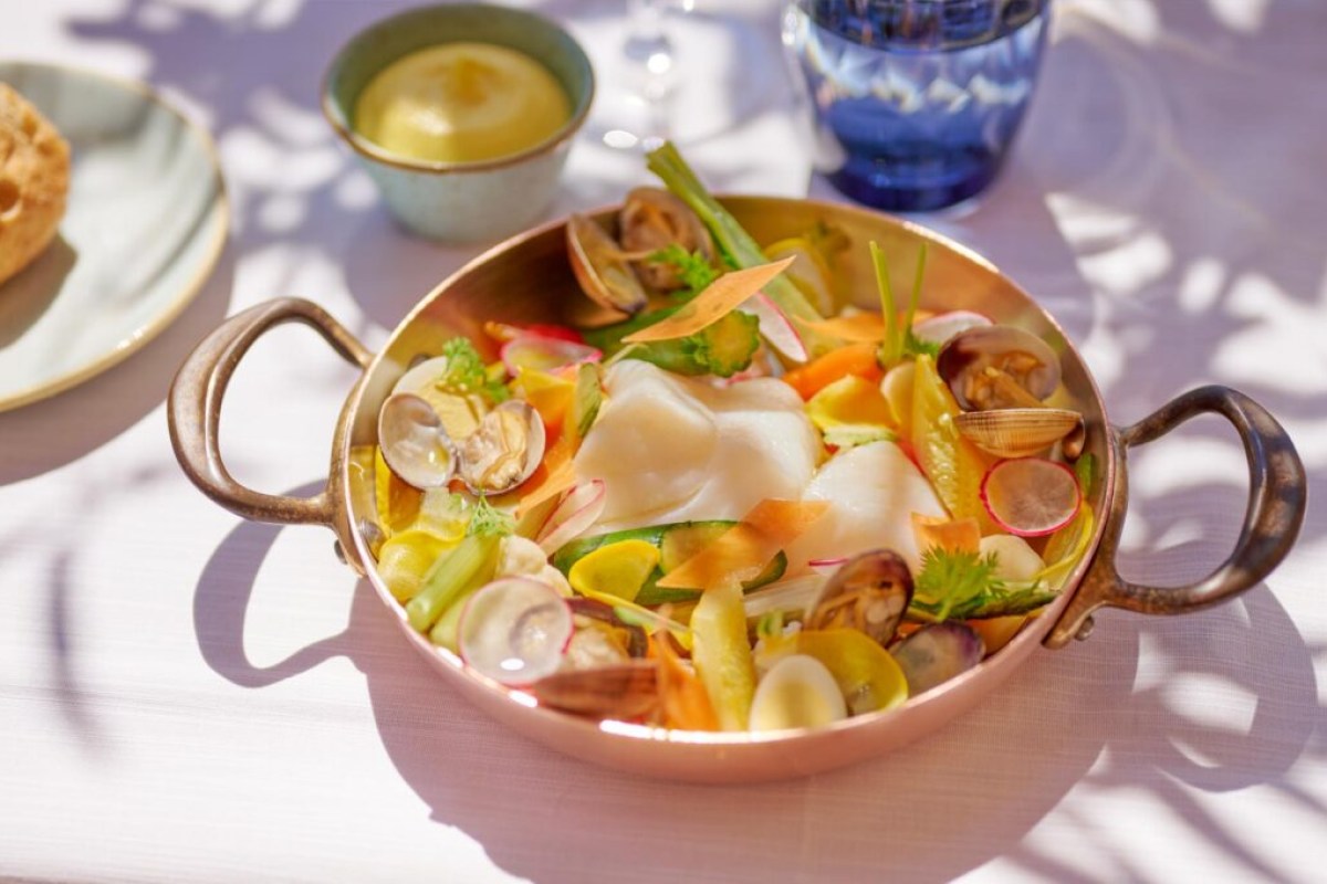 Seafood dish in copper pan with clams, vegetables and white fish
