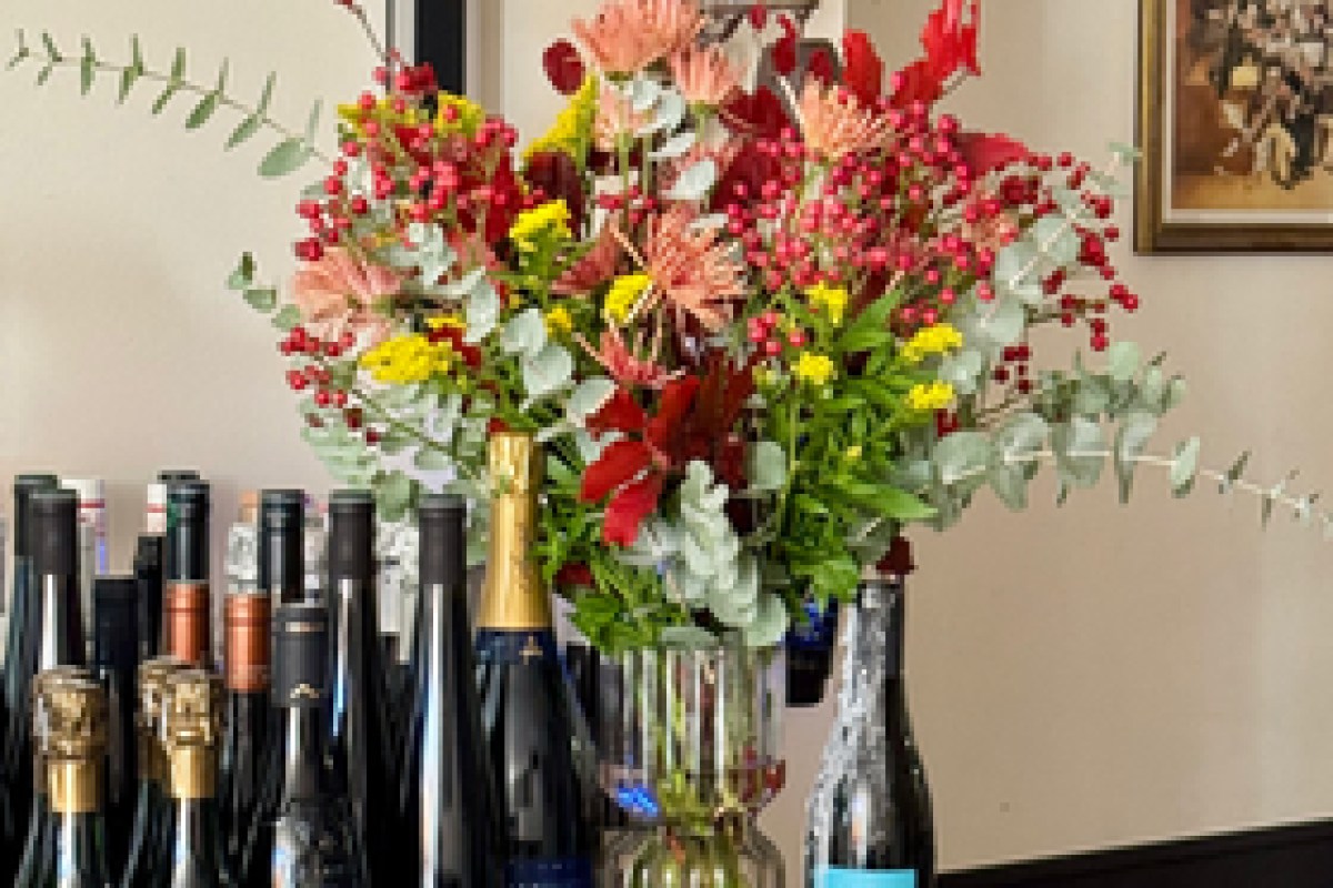 Bar area with wine and champagne bottles, a colorful flower bouquet, and a framed vintage photo on the wall