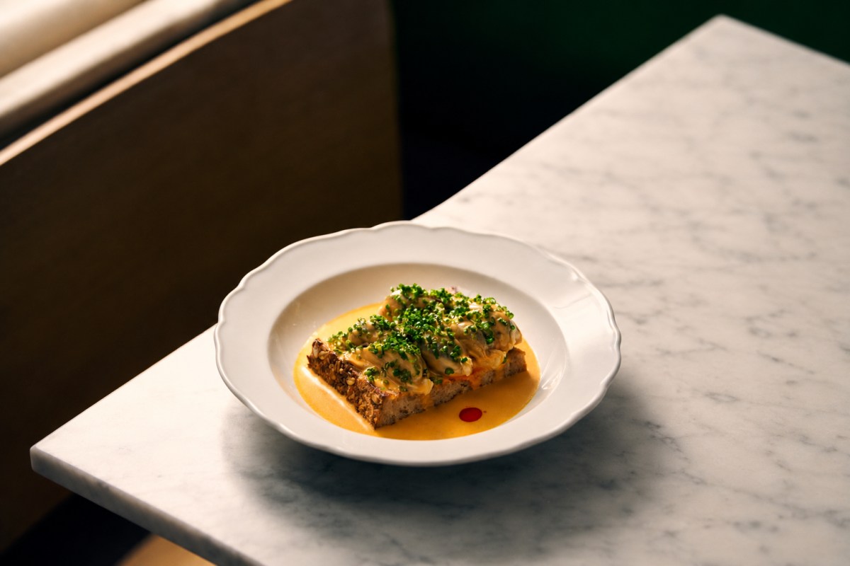 Toast topped with seafood and chives in a cream sauce, on a marble table