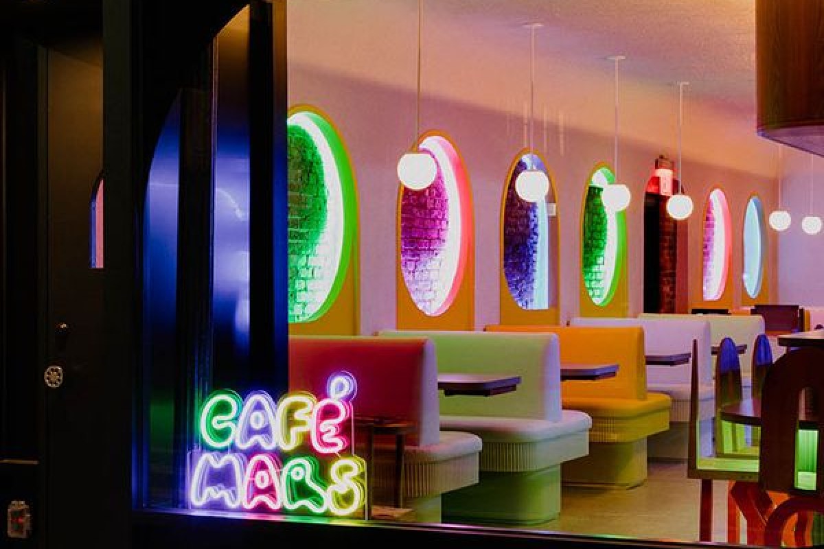 Café Mars storefront window at dusk with neon sign and colorful booth seating visible inside