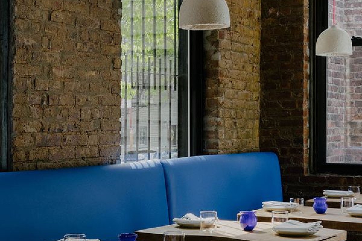 Dining room with blue banquette seating, exposed brick walls, and large windows