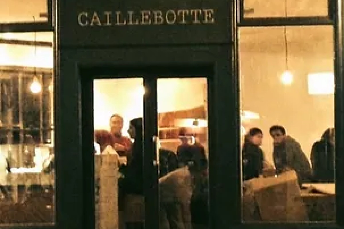 Restaurant facade at night with 'CAILLEBOTTE' signage above glass doors, diners visible inside