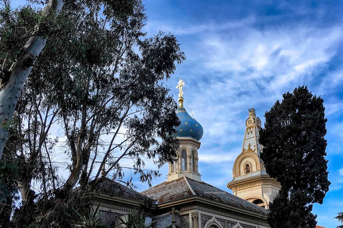 The blue onion dome with gold stars and the bell tower of the Russian church of Saint-Michel-Archange in Cannes, framed by eucalyptus and cypress trees