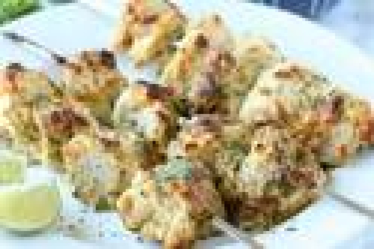 Plate of grilled seafood or chicken skewers with lime wedges