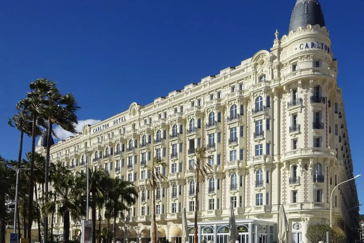 The Carlton Cannes with its white Belle Époque façade and the corner dome facing La Croisette, with palm trees in front
