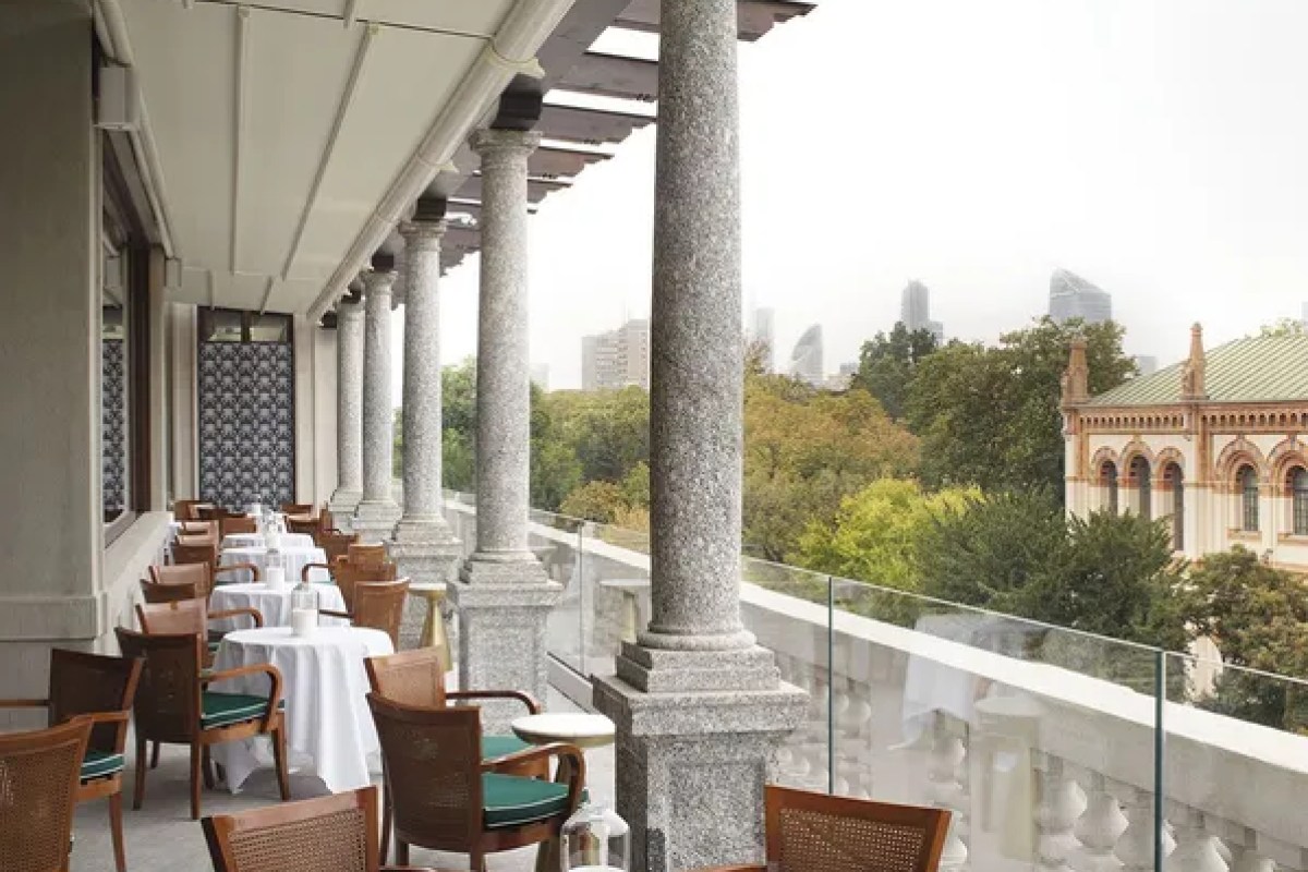 Covered terrace with columns, dining tables and city skyline view