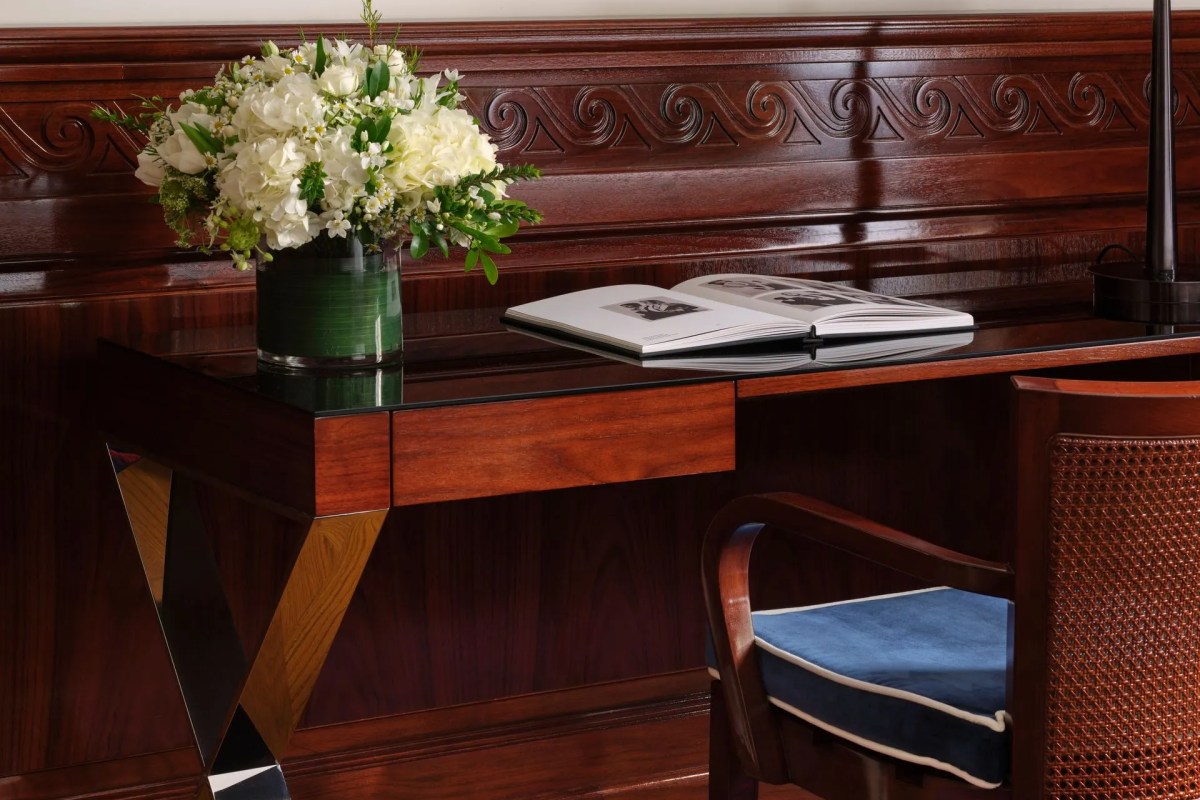 Guest room desk with wood paneling, flowers and open book