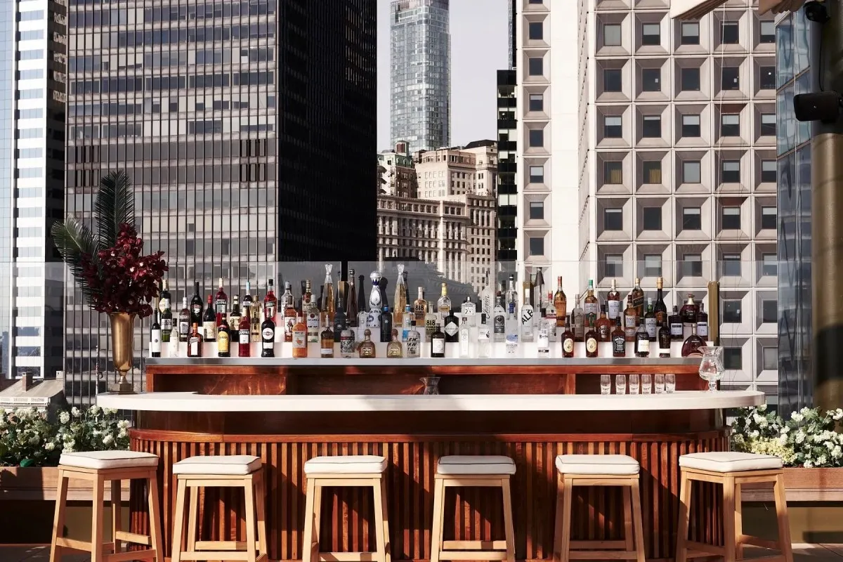 Rooftop bar with fully stocked liquor shelf against Manhattan skyline backdrop