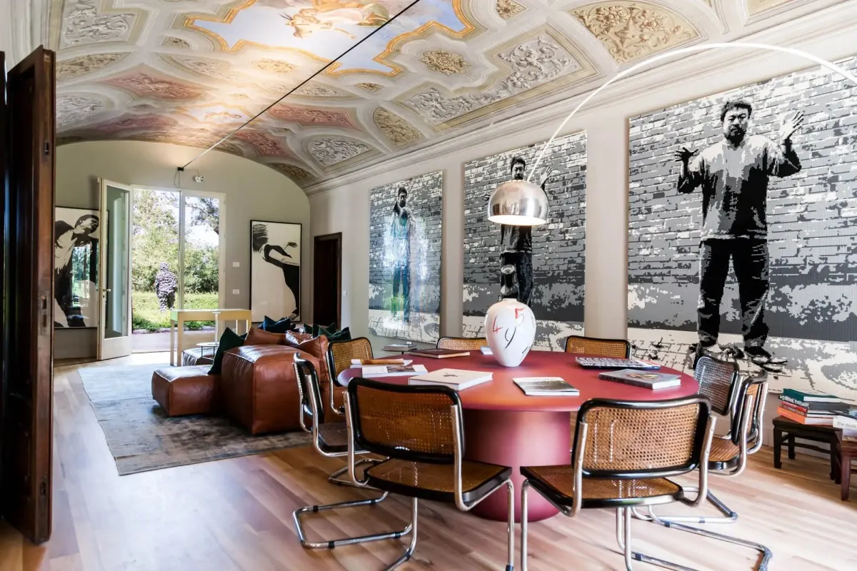 Elegant lounge with frescoed ceiling, round red table, cane chairs, and large modern artworks on the walls