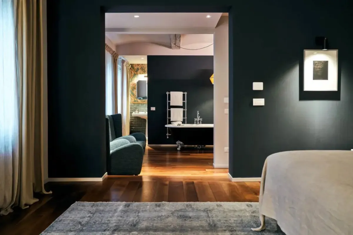 Guest suite bedroom with dark walls opening to a bathroom with a freestanding tub