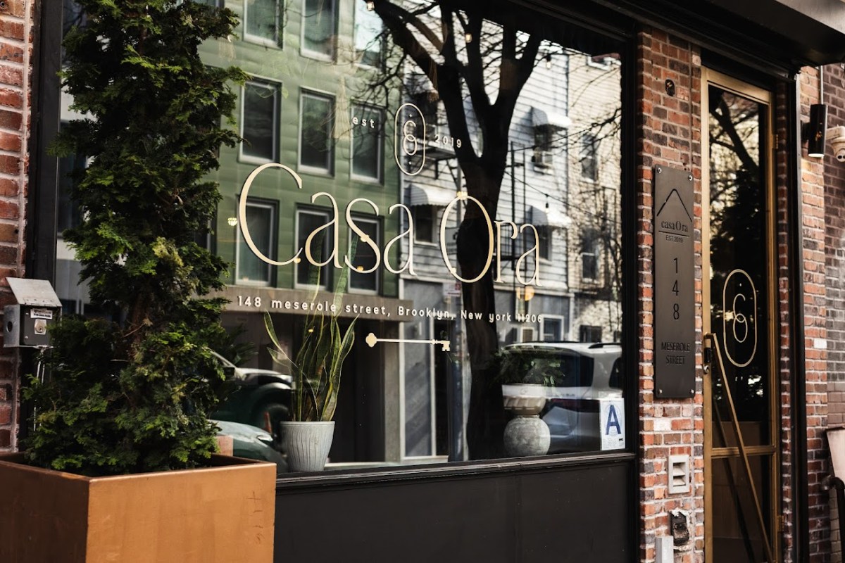 Casa Ora restaurant storefront window with gold lettering and brick facade, Brooklyn street view