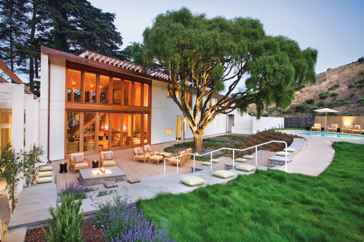 Exterior of Cavallo Point Lodge building with pool, lawn, and tree at dusk